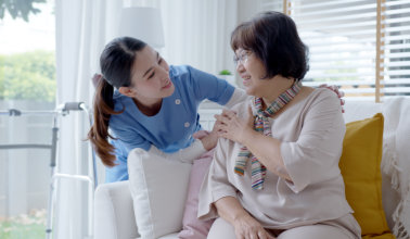 caregiver smiling while looking at the elderly woman