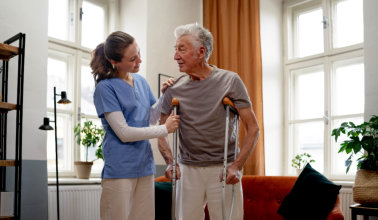 nurse assisting the elderly man with crutches