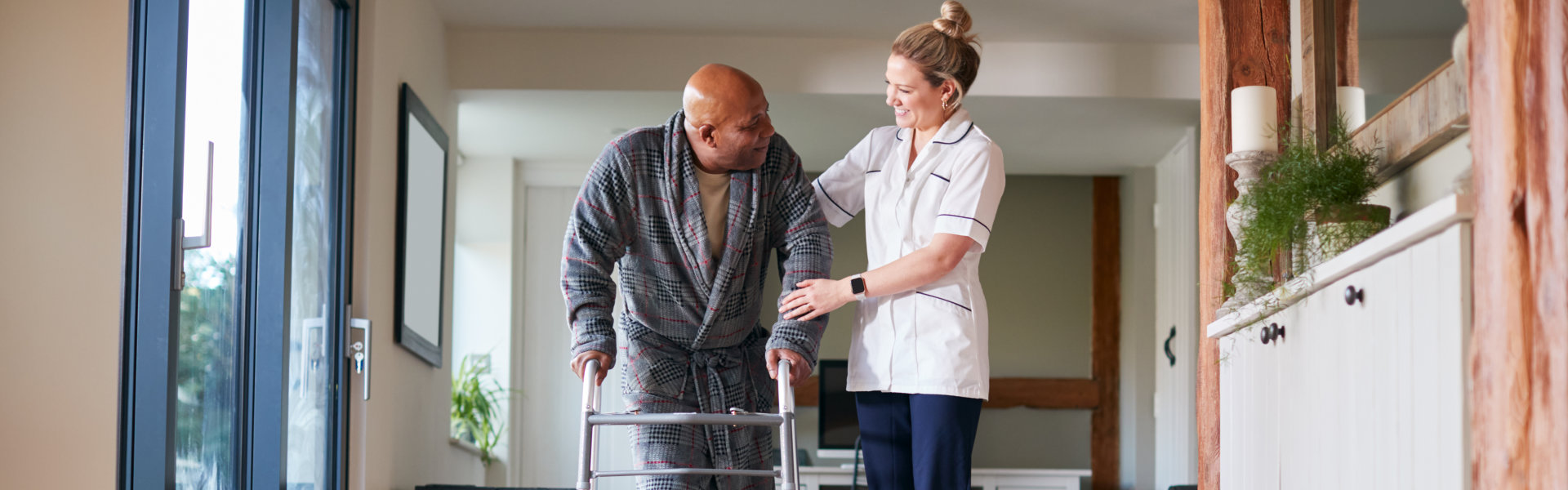 elderly man and caregiver walking in the hallway