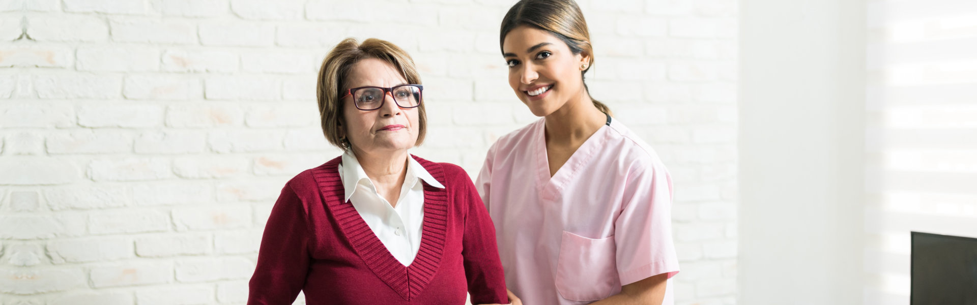 caregiver and elderly woman standing in the living room