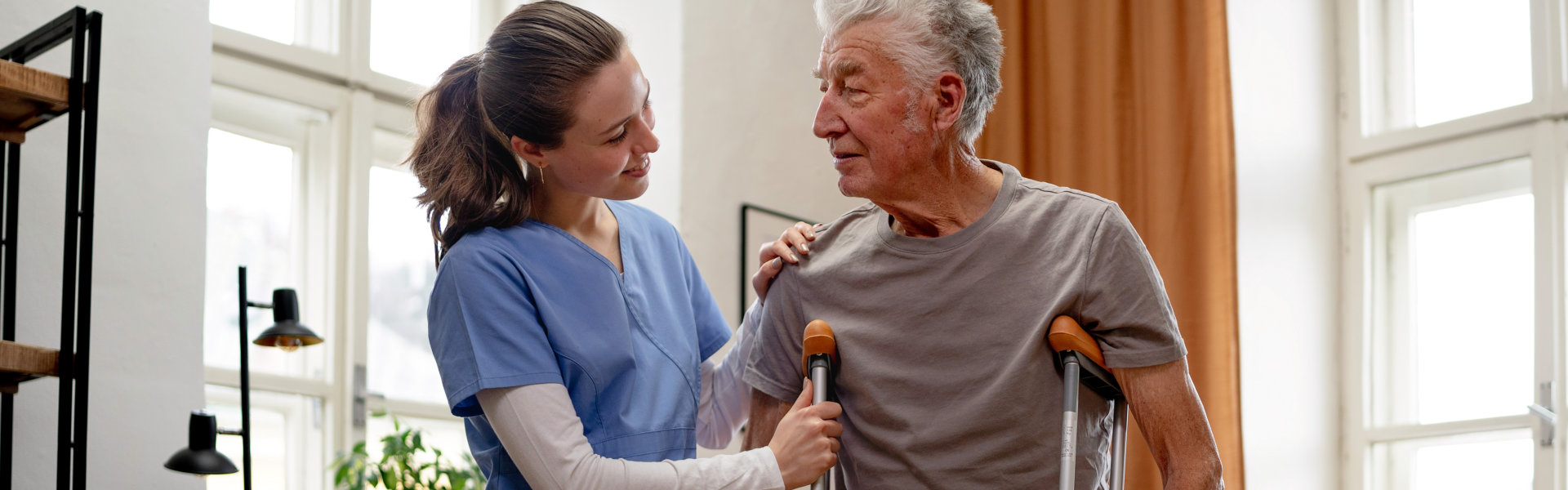 nurse assisting the elderly man with crutches