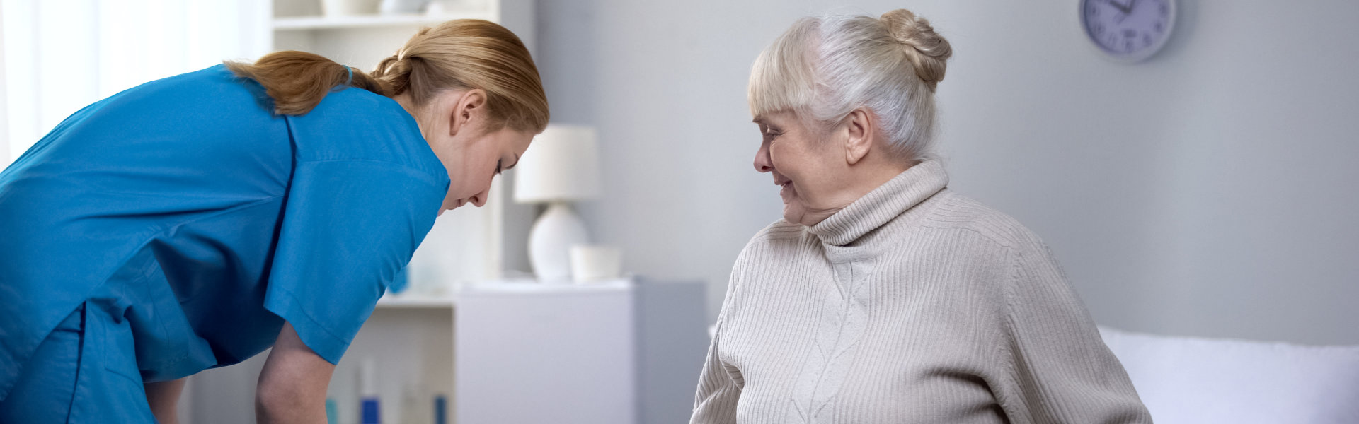 Nurse preparing clean bed-linen to female patient